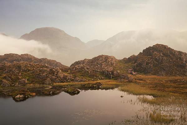 scafell pike visible between great gable and kirk fell through billowing mist from innominate tarn at sunset