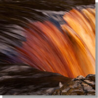 red peat tinted water flowing over rock at top of kisdon force waterfall in limestone gorge detail