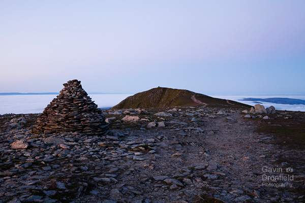 footpath over brim fell summit towards distant old man of coniston under pink dawn skies