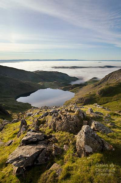 levers water tarn viewed from crags on swirl band climb with cloud inversion covering coniston water in valley