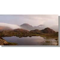 Innominate Tarn view towards red tinged Great Gable during atmospheric stormy sunset
