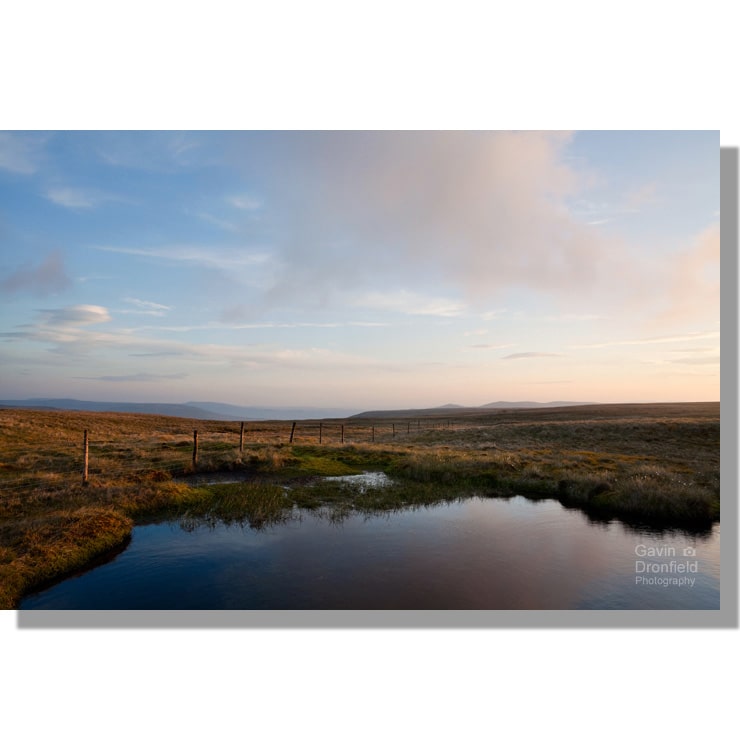 unnamed tarn and fence on wild boar fell with distant howgill fells at sunset