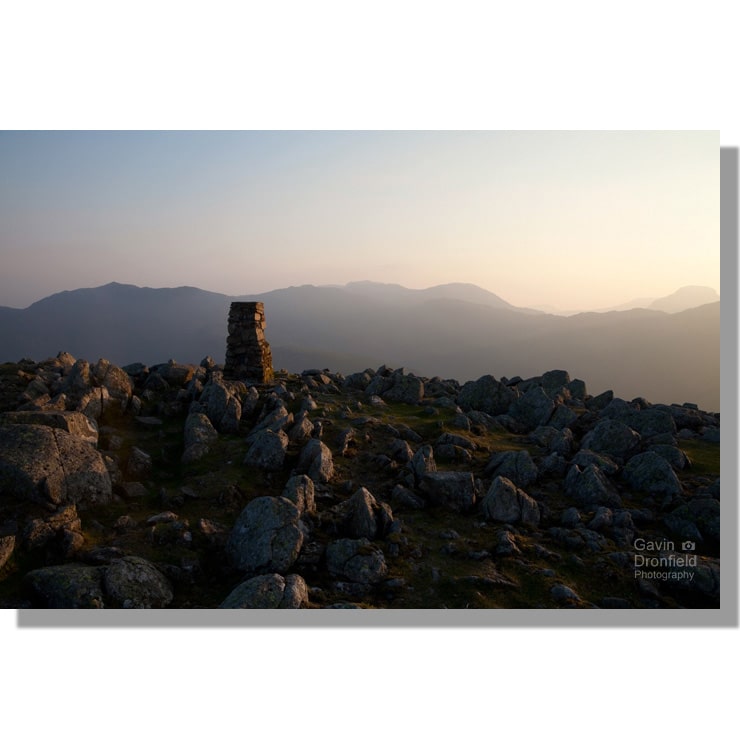 clear sunset from High Raise trig point looking towards bow fell, scafell pike and great gable
