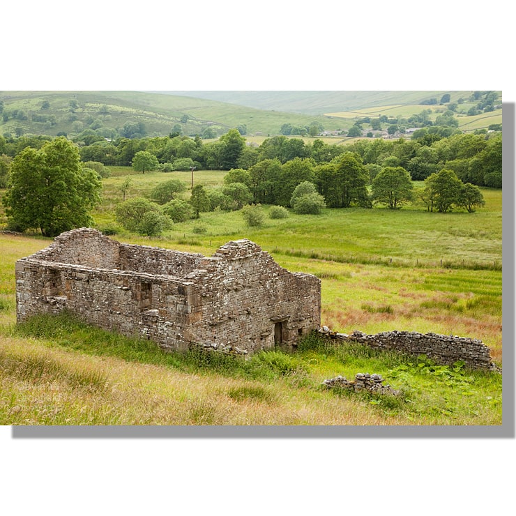 ruined dry stone barn in raydale summer meadows and distant hamlet of marsett