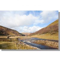 river swale meandering though winter meadows in upper swaledale valley under cloudy skies