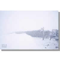 white-out at pen-y-ghent summit with dry stone wall and fingerpost under deep snow during blizzard