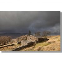 ruined farmstead high hall on high way track above mallerstang under dark brooding skies with wild boar fell in the background
