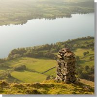 bonscale tower columnar cairn on bonscale fell overlooking ullswater amid surrounding green farm fields in summer