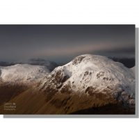 snow capped summit of great gable and kirk fell seen from scafell ridge during moody winter sunset