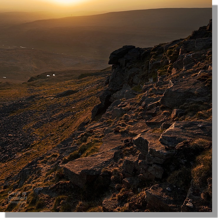 view from millstone grit crags on ingleborough summit looking over river doe during golden sunset