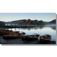 rowing boats moored on derwent water in keswick with jetties on the lake and catbells turning red at sunrise as mist rises off the water